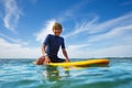 Cute young boy sit on orange surfboard in ocean Royalty Free Stock Photo