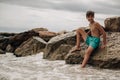 Smiling boy sitting on the beach rock