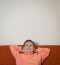 Smiling boy sitting on sofa and dreaming. Child looking up and relaxing at home. Copy-space.