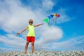 Smiling boy stand on pebble beach holding many colorful kites Royalty Free Stock Photo