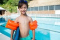 Smiling boy standing with kickboard and armband at poolside Royalty Free Stock Photo