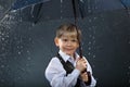 Smiling boy standing under umbrella in rain Royalty Free Stock Photo