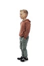 Smiling boy stands holding his hands in his pockets. Positiveness and happiness. The guy in jeans and a brown sweater. Isolated on