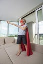 Smiling boy in super hero costume standing with arm outstretched on sofa bed at home