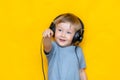 A smiling boy unplug his headphone and show plug to camera on isolated yellow background Royalty Free Stock Photo