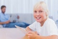 Smiling boy using tablet while his father is reading on the couch Royalty Free Stock Photo