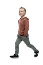 The smiling boy is walking. Preschooler in gray jeans and a brown sweater. Positiveness and movement. Isolated on white background