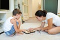 Smiling boyis playing chess with his mother while laying on a floor at home Royalty Free Stock Photo