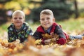 Smiling boys 6 and 10 years old lie on the ground in autumn leaves. Soft focus