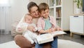 SMiling boys with young mother reading fairytale book in living room at house. Parenting, children happiness and family Royalty Free Stock Photo