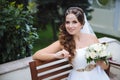The smiling bride is dressed in a Greek-style wedding dress, her hair is covered with lalatic, holds a bouquet of white Royalty Free Stock Photo