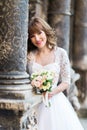 Smiling bride holding wedding bouquet on background of old building with columns, close-up Royalty Free Stock Photo