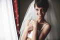 Smiling bride is posing in whiteness on the background curtains