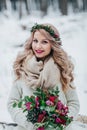 Smiling bride of Slavic appearance with a wreath of wildflowers holds a bouquet winter background. Winter wedding