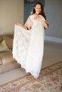 Smiling bride trying on dress while standing in living room