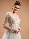 Smiling bride in white wedding dress with deep decollete smiling and looking in camera. Lace bridal gown 