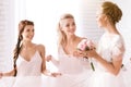 Smiling bridesmaids holding the dress of the bride