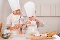 smiling brother and sister in aprons and chef hats during food preparation at table Royalty Free Stock Photo