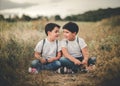 Smiling brothers sitting in the field