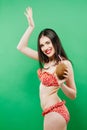 Smiling Brunette in Bright Swimsuit with Tropical Cocktail in Hands on Green Background. Royalty Free Stock Photo