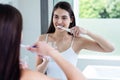 Smiling brunette brushing teeth