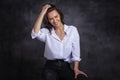 Smiling brunette businesswoman wearing white shirt and laughing against black background Royalty Free Stock Photo