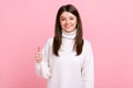 Smiling brunette female showing thumb up to camera, expressing approbation and positive emotions.