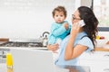 Smiling brunette holding her baby and using laptop on phone call Royalty Free Stock Photo