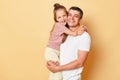 Smiling brunette man holding his little daughter, child hugging her father family looking at camera with happy faces standing in Royalty Free Stock Photo