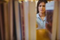 Smiling brunette picking out a book of bookshelves Royalty Free Stock Photo
