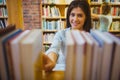 Smiling brunette picking out a book of bookshelves Royalty Free Stock Photo