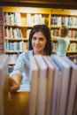 Smiling brunette picking out a book of bookshelves Royalty Free Stock Photo
