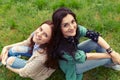 Smiling girls sitting back to back on grass Royalty Free Stock Photo