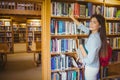 Smiling brunette student picking out book Royalty Free Stock Photo