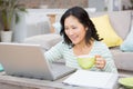 Smiling brunette using laptop and holding mug Royalty Free Stock Photo