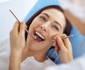 Smiling brunette woman being examined by dentist at dental clinic. Hands of a doctor holding dental instruments near Royalty Free Stock Photo