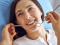 Smiling brunette woman being examined by dentist at dental clinic. Hands of a doctor holding dental instruments near Royalty Free Stock Photo