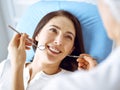 Smiling brunette woman being examined by dentist at dental clinic. Hands of a doctor holding dental instruments near Royalty Free Stock Photo