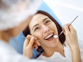 Smiling brunette woman being examined by dentist at dental clinic. Hands of a doctor holding dental instruments near Royalty Free Stock Photo