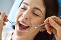 Smiling brunette woman being examined by dentist at dental clinic. Hands of a doctor holding dental instruments near Royalty Free Stock Photo