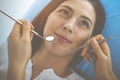 Smiling brunette woman being examined by dentist at dental clinic. Hands of a doctor holding dental instruments near Royalty Free Stock Photo