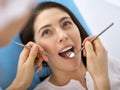 Smiling brunette woman being examined by dentist at dental clinic. Hands of a doctor holding dental instruments near Royalty Free Stock Photo