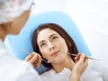 Smiling brunette woman being examined by dentist at dental clinic. Hands of a doctor holding dental instruments near Royalty Free Stock Photo