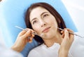 Smiling brunette woman being examined by dentist at dental clinic. Hands of a doctor holding dental instruments near Royalty Free Stock Photo