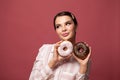 Smiling brunette woman with chocolate ans sugar donut and looking up over red background