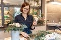 Smiling brunette woman collecting flower gift box. Florist. Floristic workshop. Master class teaching concept