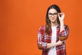 Smiling brunette woman in eyeglasses and casual posing with crossed arms and looking at the camera over orange background Royalty Free Stock Photo