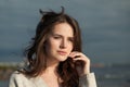 Smiling brunette woman with fresh skin, natural make-up and healthy wavy brown hair enjoying the sunny morning and sea air. Royalty Free Stock Photo