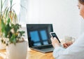 Smiling brunette woman using mobile phone with opened laptop at the home Royalty Free Stock Photo