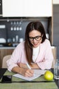 Smiling woman writing on note pad in the kitchen Royalty Free Stock Photo